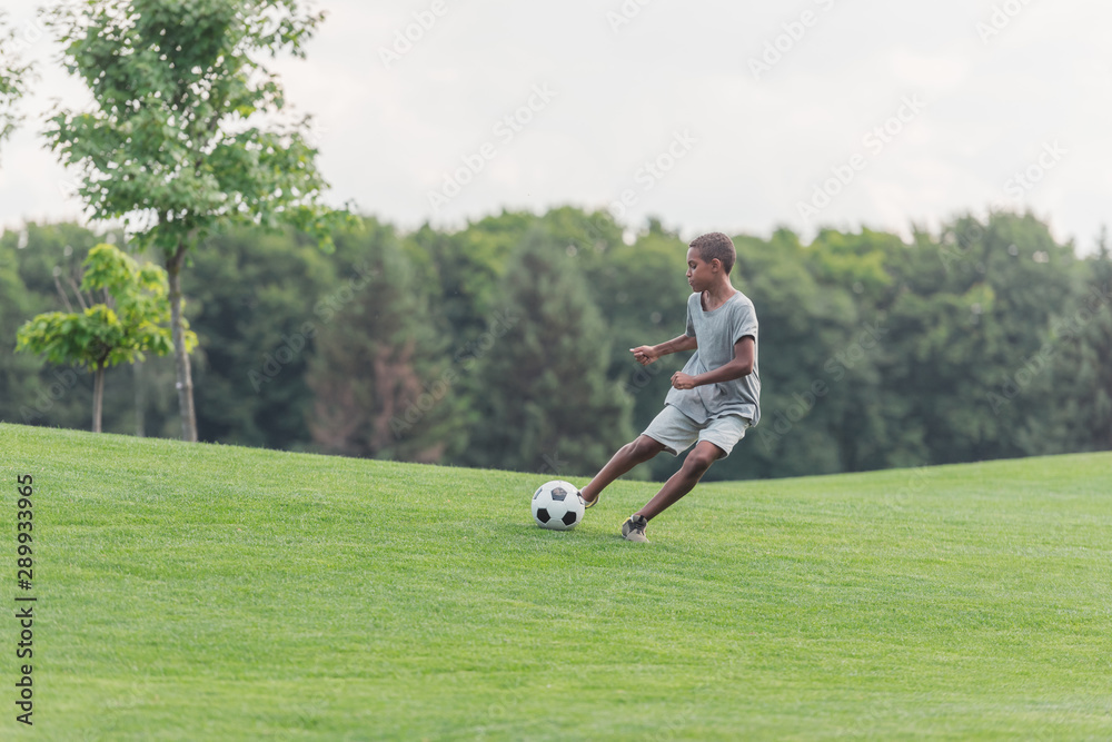 cute african american boy playing football on green grass cute african american boy playing football on green grass