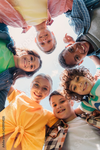 bottom view of cheerful multicultural kids looking at camera