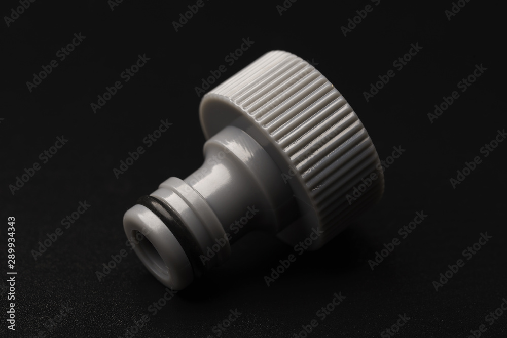Adapter for watering from a hose. Hose adapter on a black background close-up. Adapter. Adapter for watering from a hose. Hose adapter on a black background close-up. Adapter.