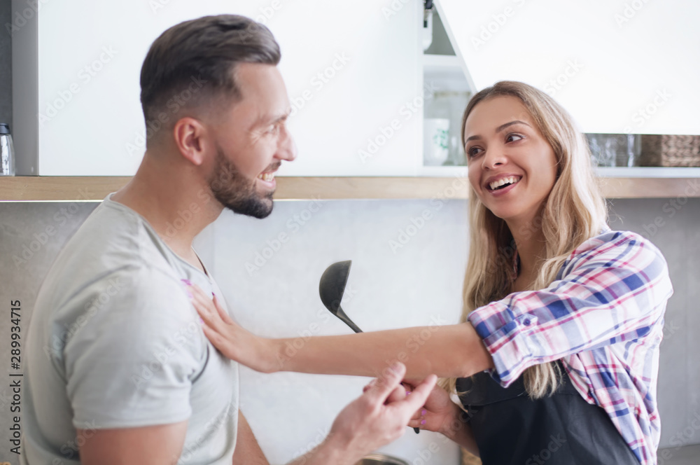 Obraz premium Smiling young couple cooking food in the kitchen