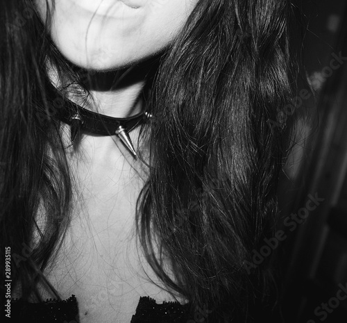 Black and white portrait of a beautiful gothic woman in black corset and spiked collar