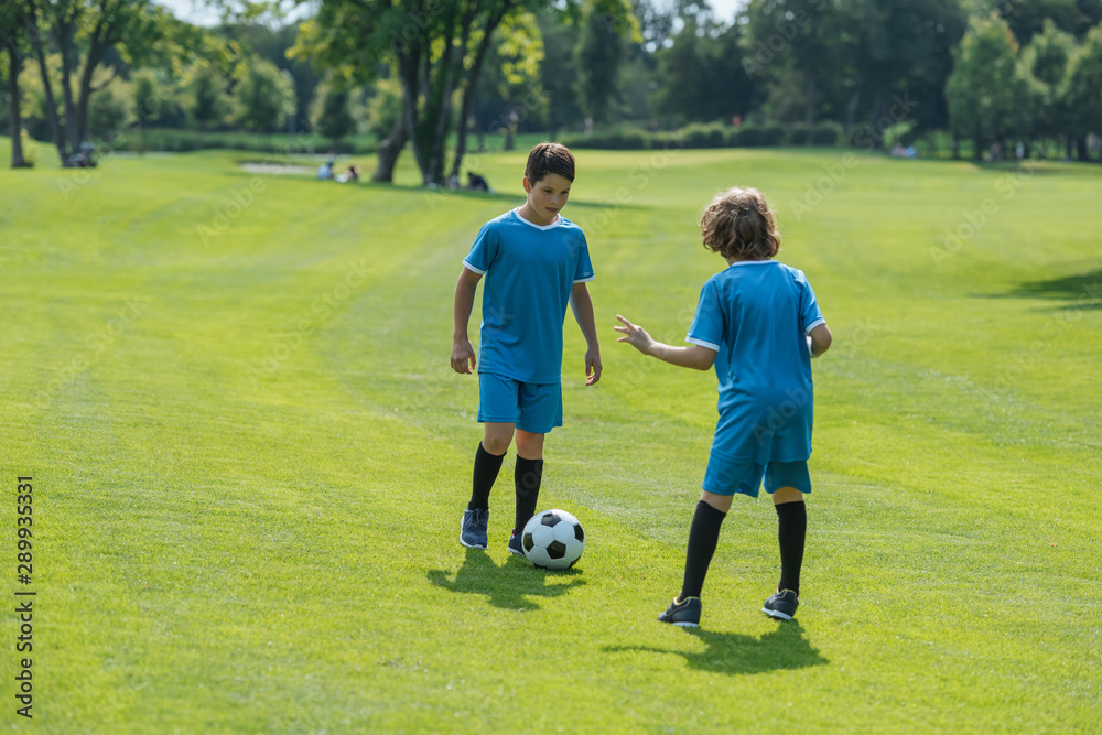 back view of curly boy playing football with friend back view of curly boy playing football with friend
