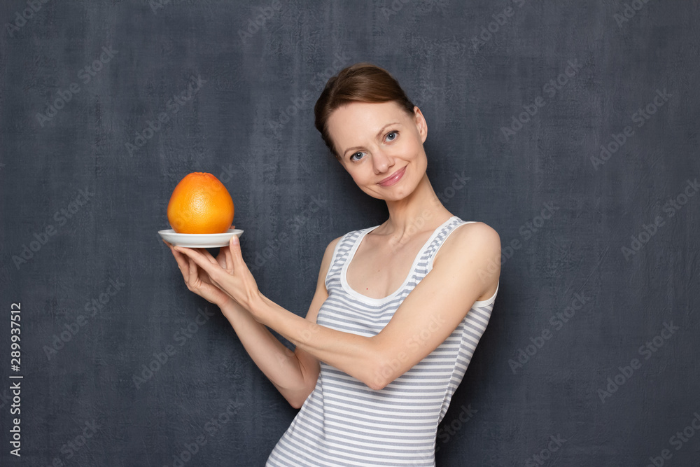 Portrait of happy girl holding saucer with ripe grapefruit Portrait of happy girl holding saucer with ripe grapefruit