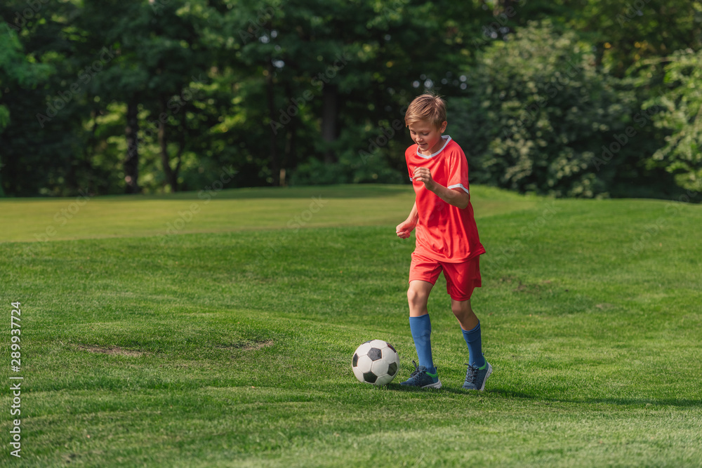 happy kid in sportswear running while playing football happy kid in sportswear running while playing football
