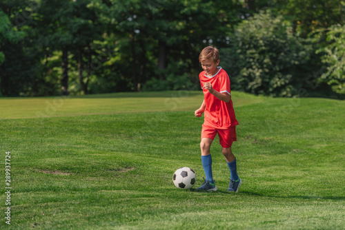 happy kid in sportswear running while playing football © LIGHTFIELD STUDIOS