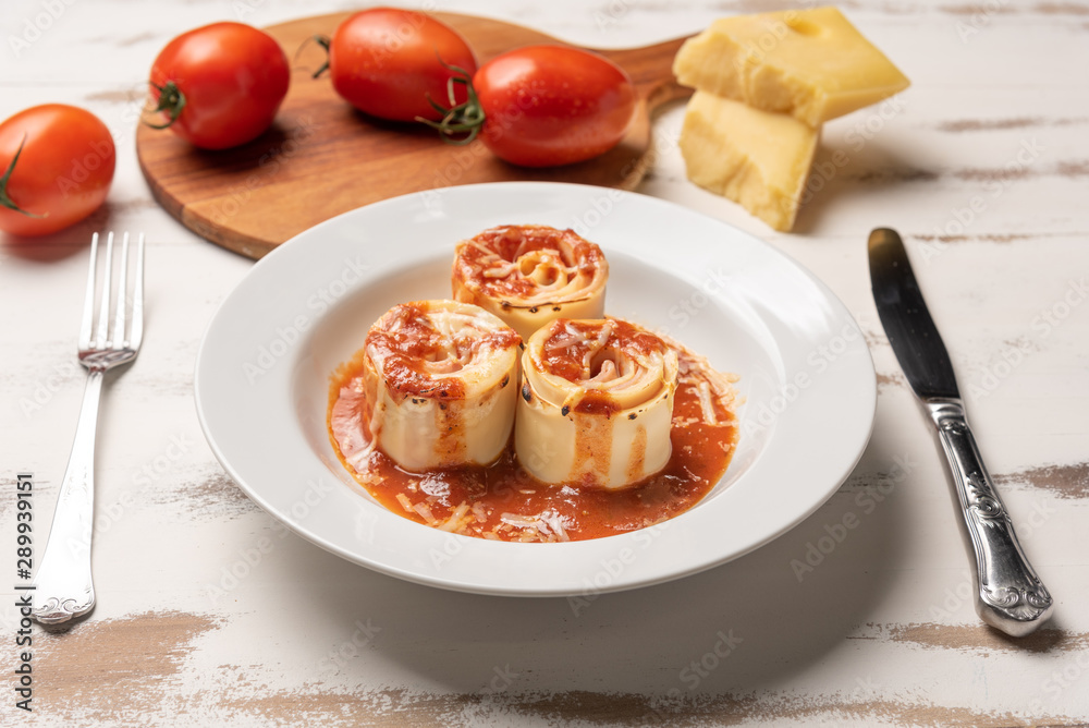 Traditional Italian Rondelli pasta with tomato sauce on rustic white wooden table background, soft light