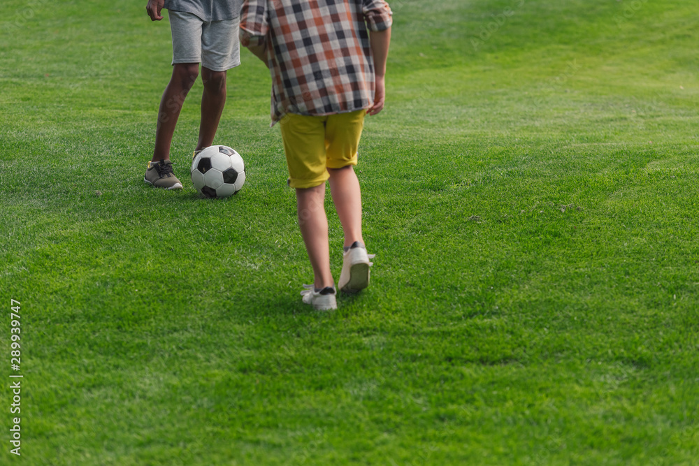 cropped view of multicultural boys playing football cropped view of multicultural boys playing football