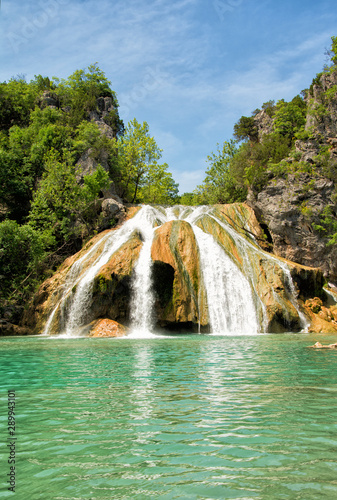 Waterfall at Turner Falls, Oklahoma, with beautiful aqua colored water under blue spring sky