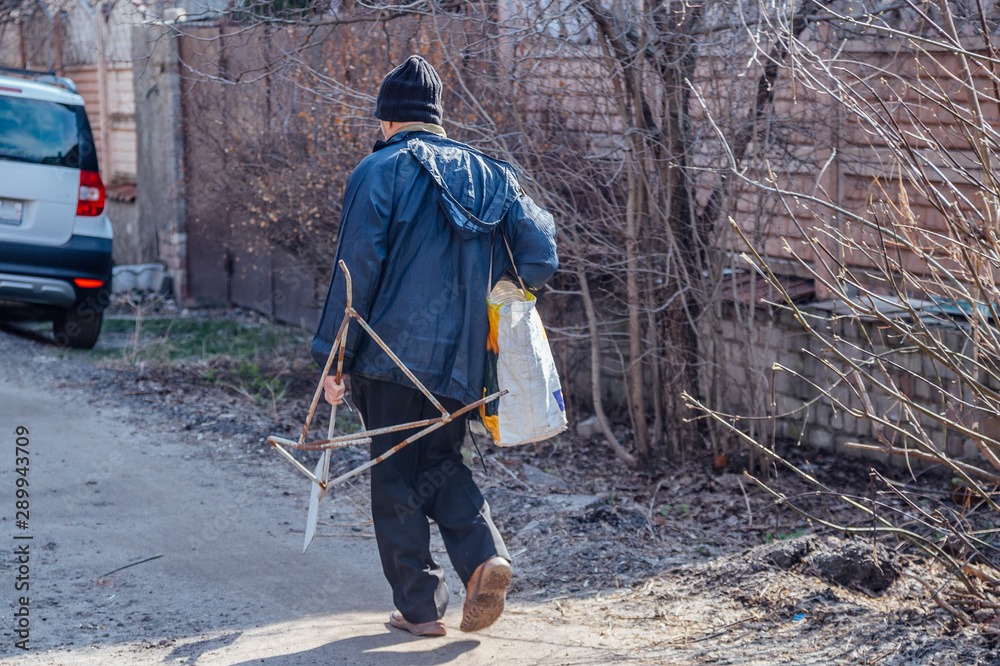 A rear view of homeless man walking with bag and scrap metal A rear view of homeless man walking with bag and scrap metal