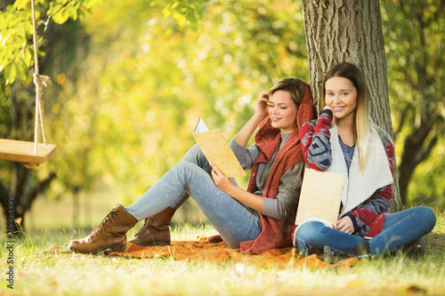 Beautiful girlfriends reading a books in park