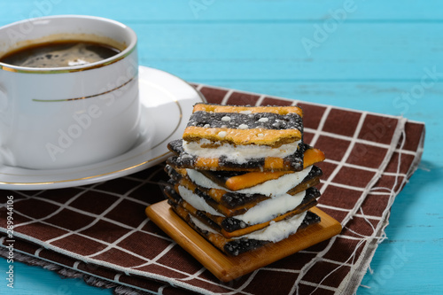 side view cup of coffee and stack of sandwich biscuits with white cream filling photo