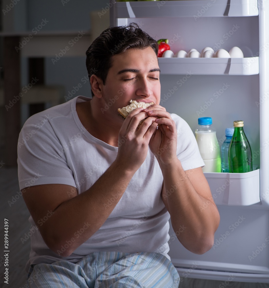 Man at the fridge eating at night Man at the fridge eating at night