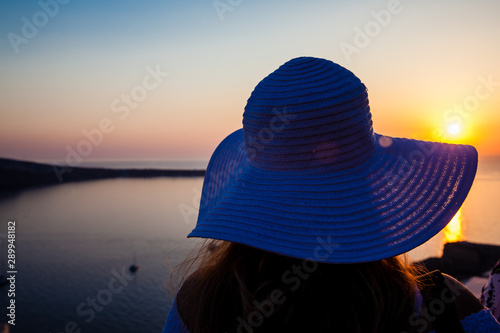 Young woman looking at the beautiful sunset at the famous Caldera of Santorini Island in Oia City