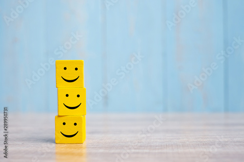 smile face on yellow wood cube. Service rating, ranking, customer review, satisfaction and emotion concept. photo