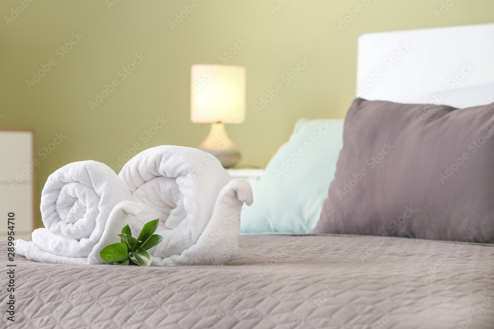 Soft clean towels rolled in shape of snail on bed