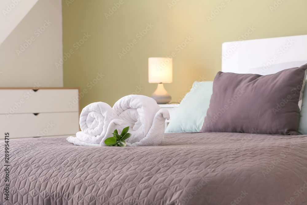 Soft clean towels rolled in shape of snail on bed