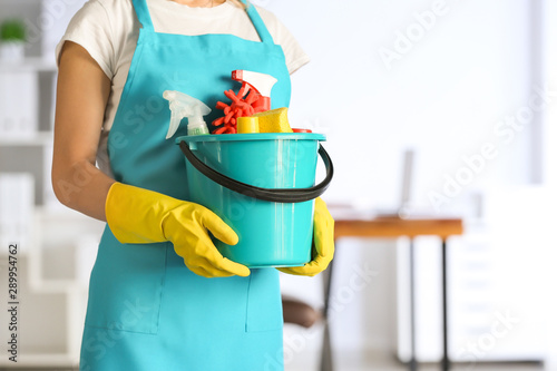 Female janitor with set of cleaning supplies in office photo