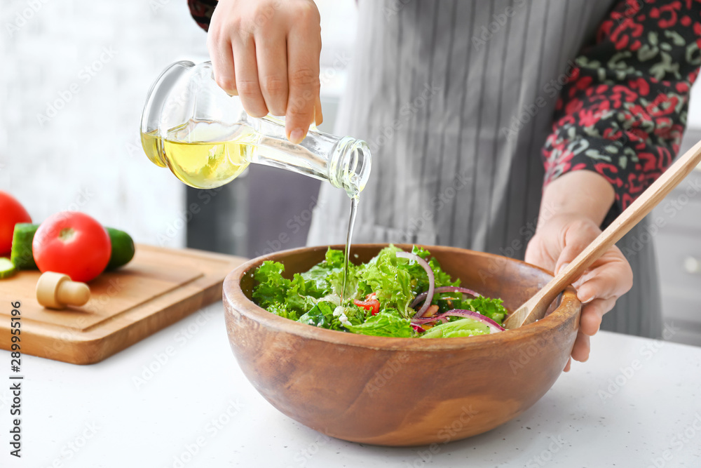 Woman preparing fresh salad at table, closeup Woman preparing fresh salad at table, closeup