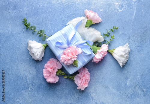 Beautiful flowers and gift on color background
