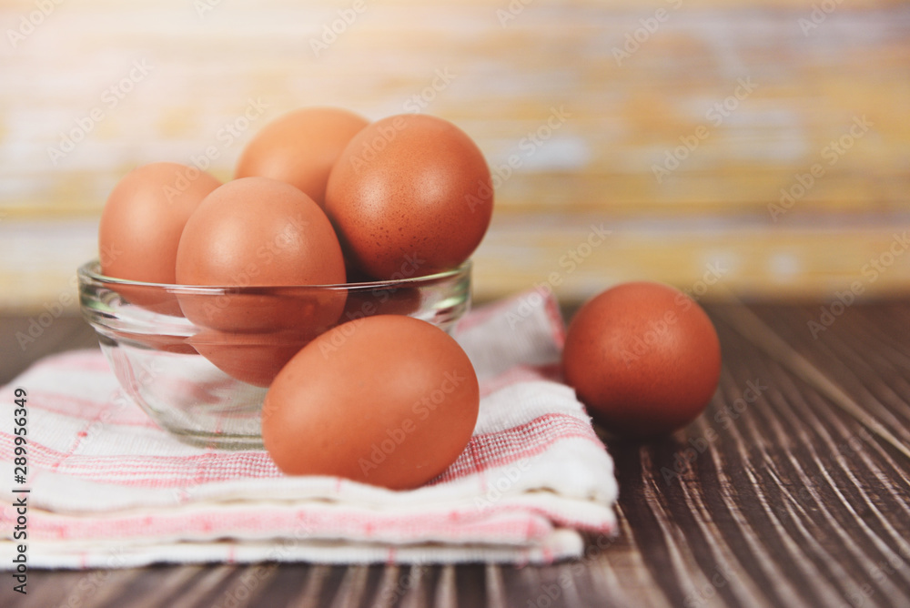 Fresh egg bowl on tablecloth on the wooden table background - Raw chicken eggs collect from the farm products natural eggs for food Fresh egg bowl on tablecloth on the wooden table background - Raw chicken eggs collect from the farm products natural eggs for food