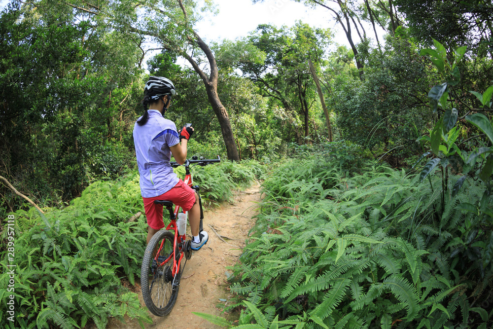 Cyclist using smart phone while riding bike on the rainforest trail Cyclist using smart phone while riding bike on the rainforest trail
