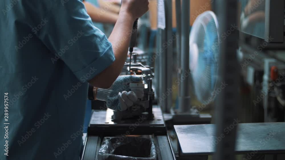 Engineer screwing bolt in metal appliances at assembly line on factory Engineer screwing bolt in metal appliances at assembly line on factory