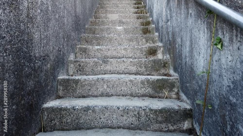 Walking up sandy concrete stairs with a steel handrail at a beach with grass and berry shrubs on the sides in slow motion. photo