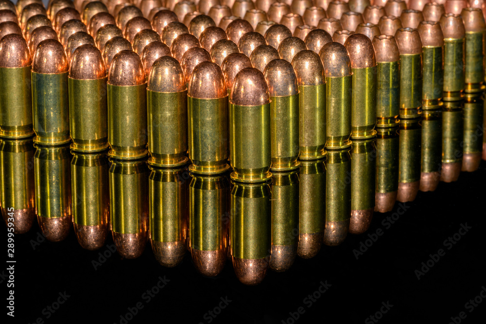 Neat Rows of handgun ammunition on black background with reflection