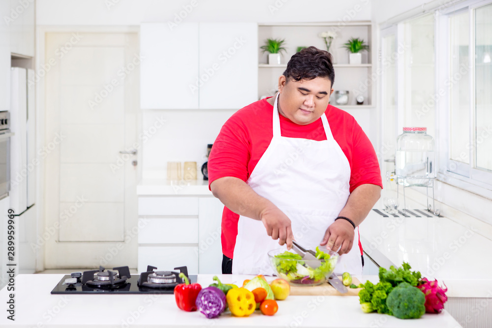 Young fat man mixing a bowl of fresh salad Young fat man mixing a bowl of fresh salad