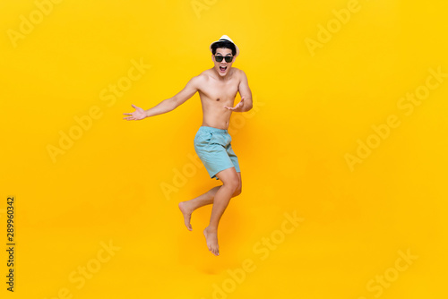 Amazed shirtless handsome Asian tourist man jumping