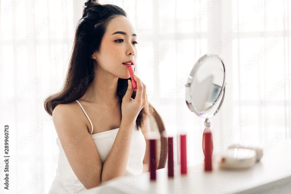 Smiling beautiful woman fresh healthy skin looking on mirror and enjoying applying lips with red lipstick at home.facial beauty and cosmetic concept Smiling beautiful woman fresh healthy skin looking on mirror and enjoying applying lips with red lipstick at home.facial beauty and cosmetic concept