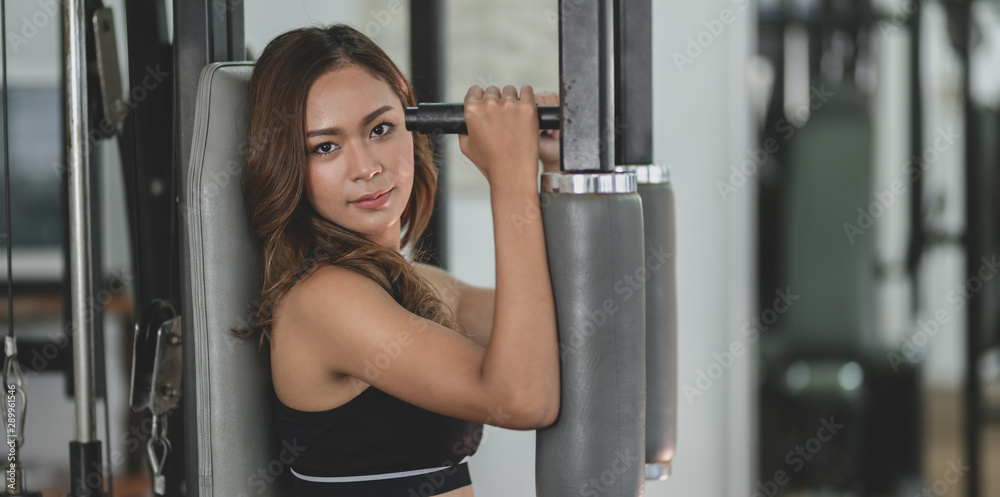 Young asian woman lifting the weight on weight-lifting machines Young asian woman lifting the weight on weight-lifting machines