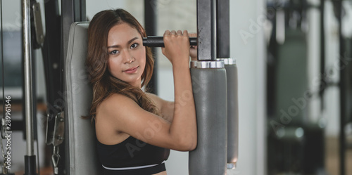 Young asian woman lifting the weight on weight-lifting machines