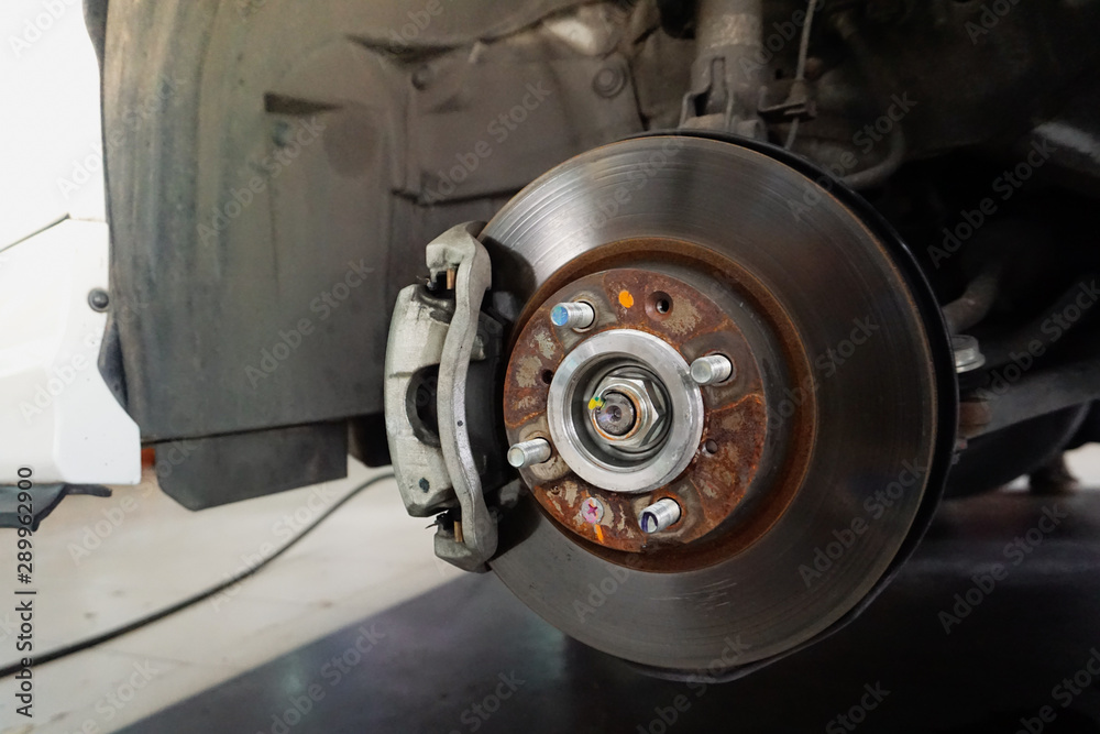 Car brake repairing in garage.Close up. Disc brake of the vehicle for repair, in process of new tire replacement. Car brake repairing in garage.Close up. Disc brake of the vehicle for repair, in process of new tire replacement.