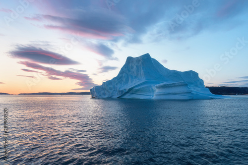 Iceberg at sunset. Nature and landscapes of Greenland. Disko bay. West Greenland. Summer Midnight Sun and icebergs. Big blue ice in icefjord. Affected by climate change and global warming.