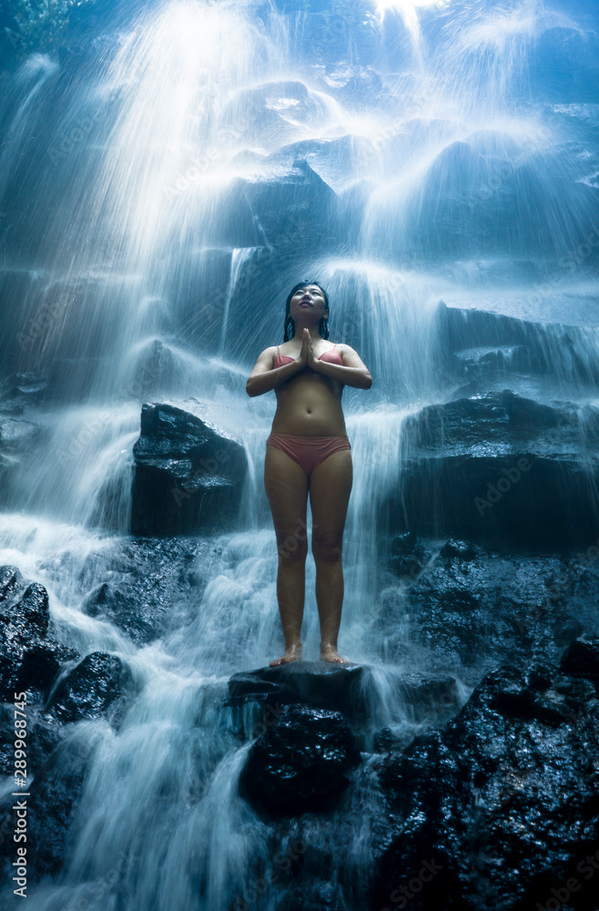 Obraz premium natural portrait of young beautiful and happy Asian Chinese woman in bikini enjoying nature at tropical paradise waterfall with magical feeling in soul inspiration