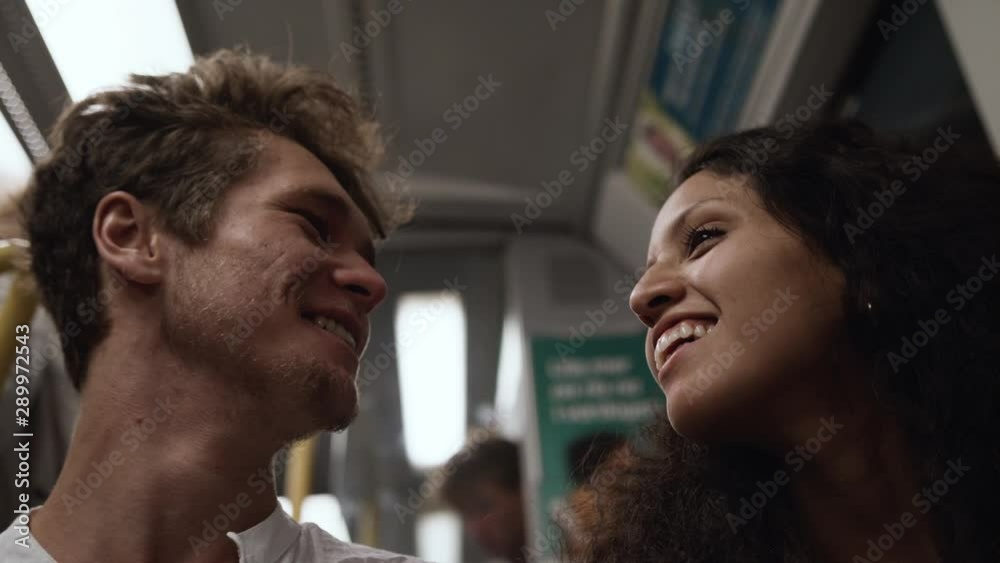 Low angle shot of a young loving couple laughing on the subway.