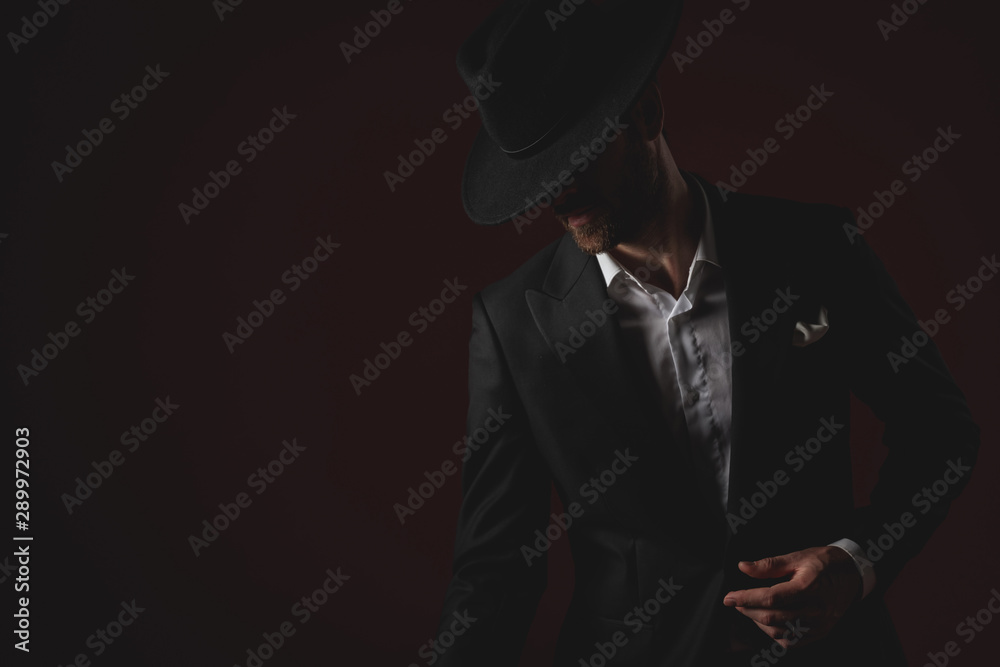 mysterious young man arranging his coat on black background mysterious young man arranging his coat on black background