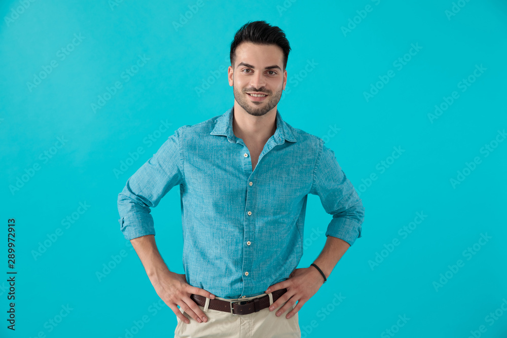 man in blue shirt standing with hands on waist man in blue shirt standing with hands on waist