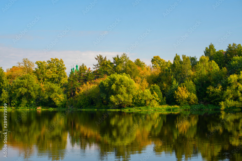 early autumn - trees beginning to turn yellow and reflection in the river early autumn - trees beginning to turn yellow and reflection in the river