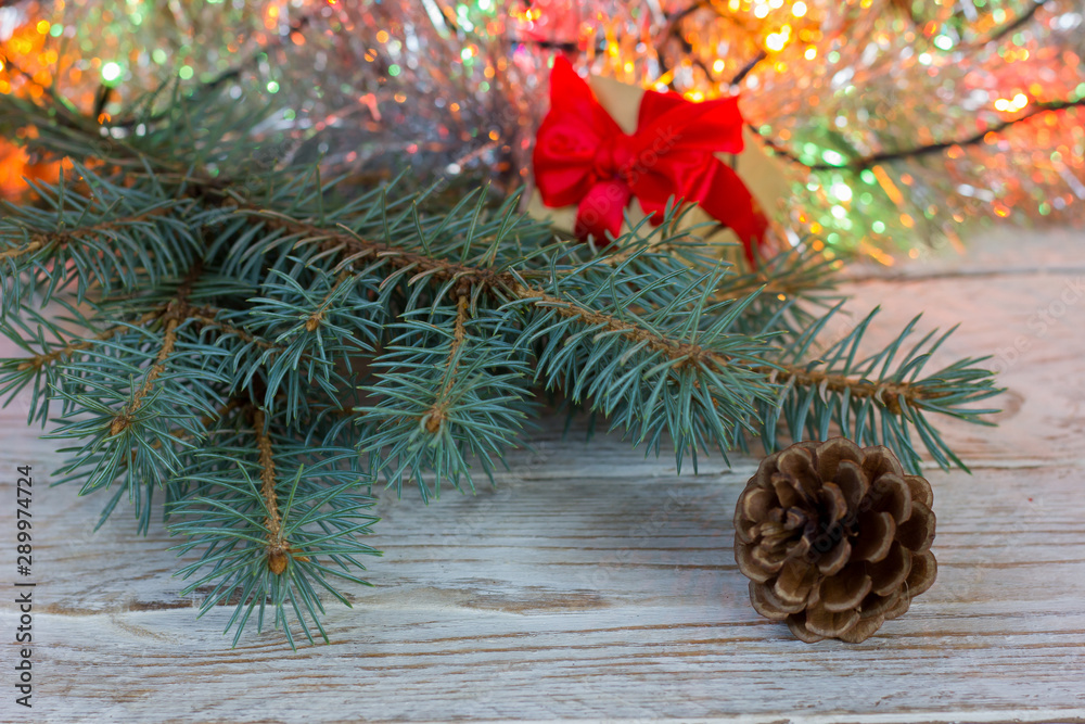 Greeting card. Gift with a red bow, fir cone on a wooden background, fir branch, bokeh. Greeting card. Gift with a red bow, fir cone on a wooden background, fir branch, bokeh.