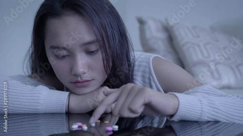 Sad teenage girl addict counting medicines or drugs on the table in the living room at home. Shot in 4k resolution