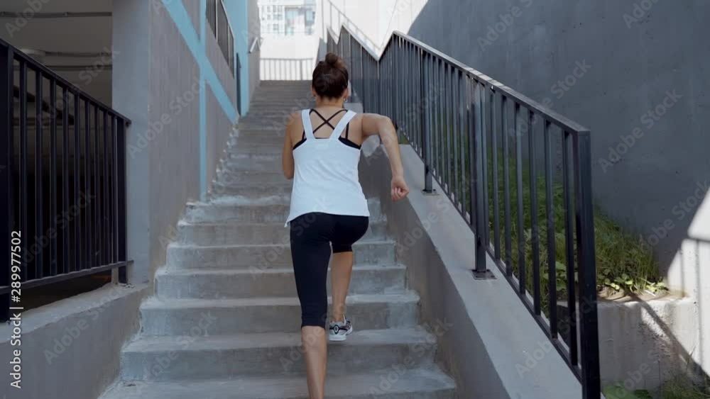 Running on stairs woman doing run up on staircase. Female runner