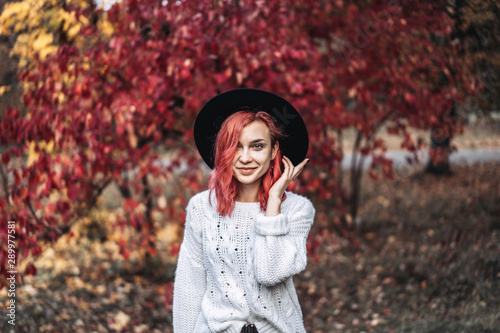 Pretty girl with red hair and hat walking in the park, autumn time.