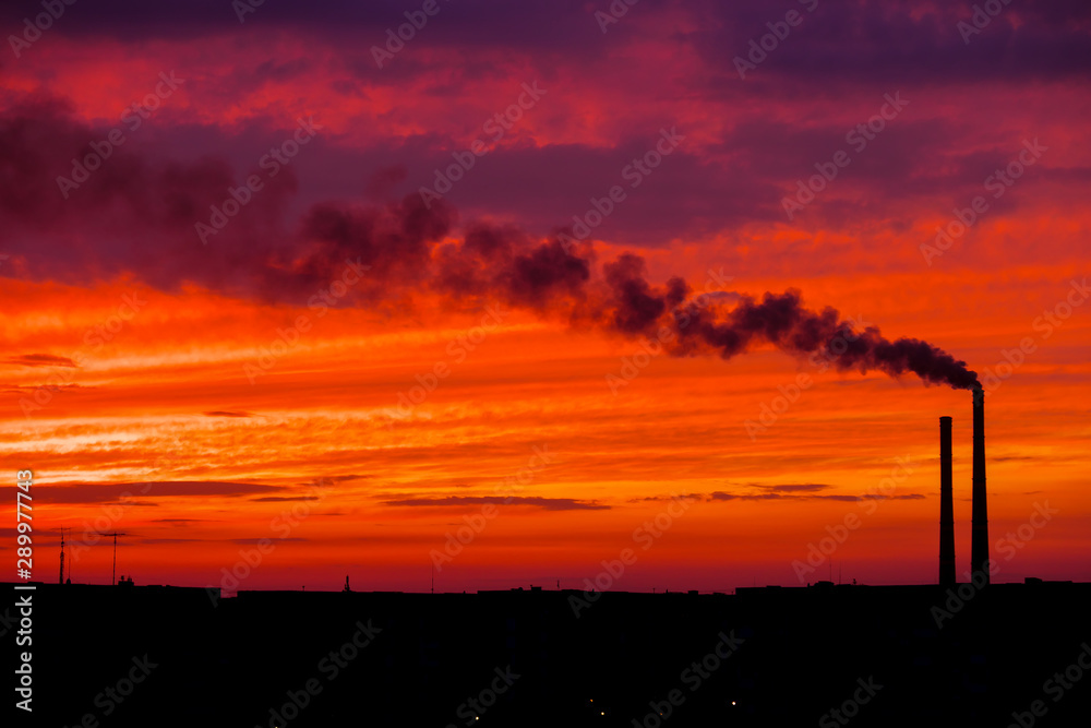 Colorful Magic Sunset. Roofs of city houses during sunrise. Dark smoke coming from the thermal power plant pipe.