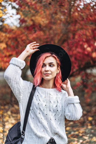 Pretty girl with red hair and hat walking in the park, autumn time.