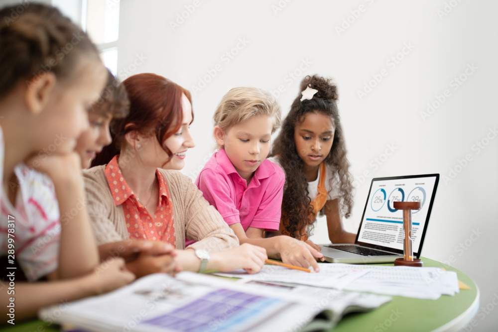 Children discussing final test with their pleasant smiling teacher Children discussing final test with their pleasant smiling teacher