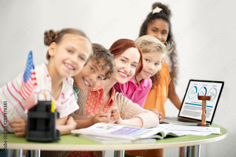 Teacher and children sitting at the table near laptop Teacher and children sitting at the table near laptop