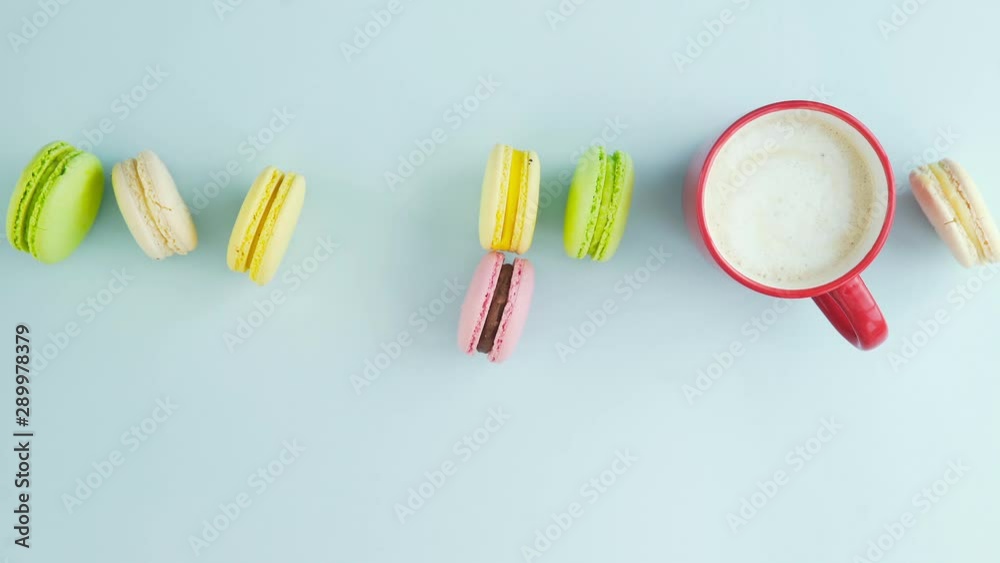 Macaroons or macaron on pastel blue surface with coffee in red cup. Macaroons or macaron on pastel blue surface with coffee in red cup.