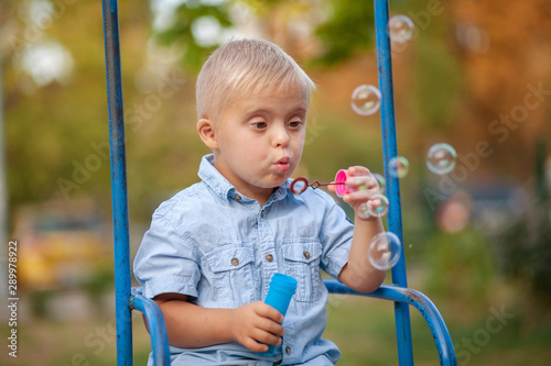 Boy with Down syndrome blowing soap bubbles, cute European child with a genetic abnormality, disabled children, extra chromosome, psychiatric illness in children.